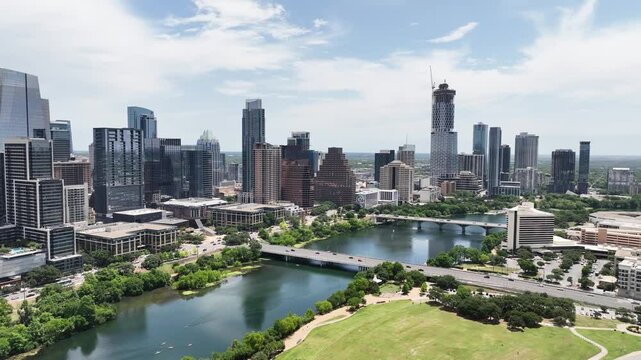 Dynamic Austin scene: Lady Bird Lake, downtown skyline. Green park, running, kayaks. Constant busy traffic. Urban nature.