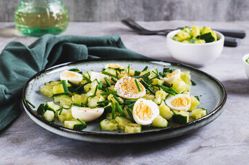 Fresh salad of cucumbers, quail eggs and green onions on a plate on the table