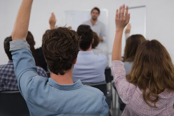young professional raising their hand during business meetings