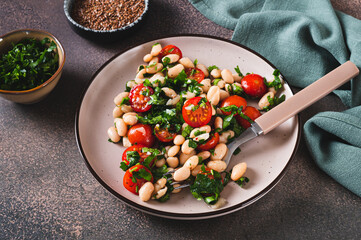 Vegetarian white bean, tomato and herb salad on a plate on the table