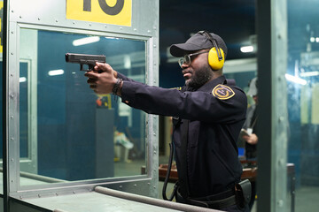 African American officer practicing marksmanship wearing earmuffs and safety equipment at shooting range aiming firearm reflecting focus and precision