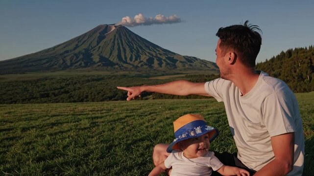 Father points at the impressive mount komagatake volcano in hokkaido, japan, sharing a moment of awe and wonder with his young son amidst a serene natural landscape