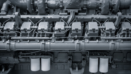 The engine is a massive piece of machinery with many different parts. It is made of gray metal and has a very industrial appearance. The engine is likely used for heavy-duty tasks