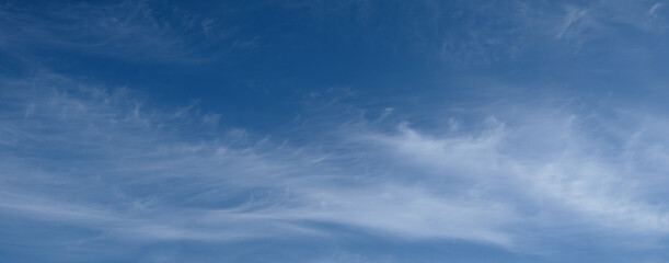 Obraz premium The sky is blue with white clouds. The clouds are fluffy and scattered. The sky is clear and bright.