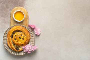 Fresh raisin danish pastry with cup of orange juice and pink carnations on rustic background