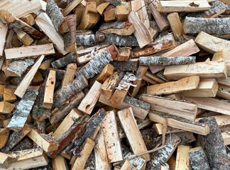 Chopped firewood for the winter. A lot of firewood - harvesting wood for heating the house.A stack of firewood with a hand chopping block. Chopped firewood backgrounds. Wooden, natural background.
