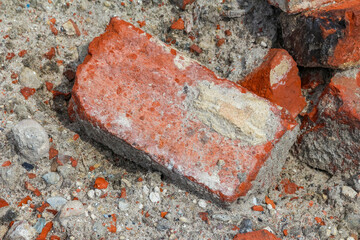 Single red brick piece standing upright among scattered concrete and brick debris on construction...