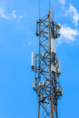 Vertical perspective of telecommunications tower with multiple antenna arrays against clear blue sky
