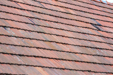 Close-up of aged terracotta roof tiles with visible wear and tear, highlighting their weathered texture,