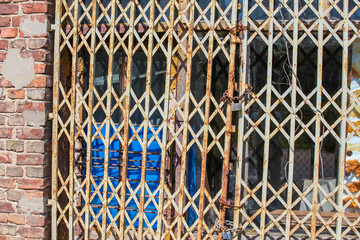 Decorative metal security gate with diamond lattice pattern casting geometric shadows on blue door...