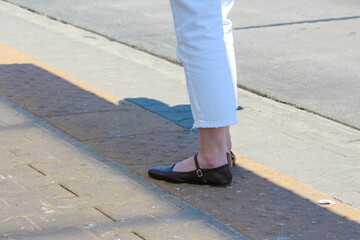 Close-up of brown leather shoe on concrete pavement showing walking detail
