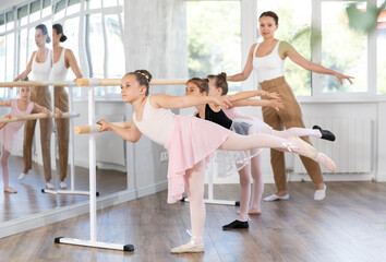 Little girls ballet lovers learn to perform arabesque pose in a choreography studio © JackF