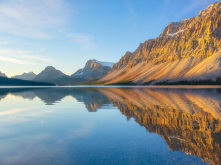 Bow lake, Alberta, Canada. Mountain landscape during sunrise. Reflections on the surface of the water. Sunbeams in a valley. Background, wallpaper, postcards.
