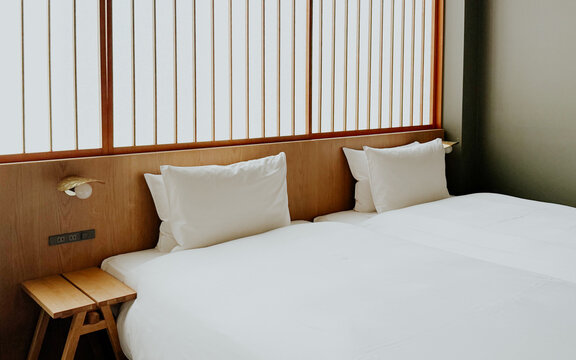 Minimalist Japanese hotel room with twin beds and soft white bedding, shoji screen. Modern ryokan interior 