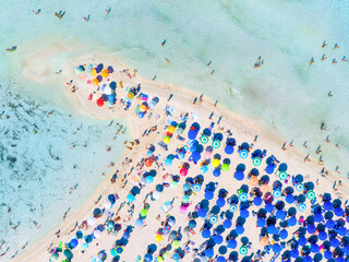Summer vacation and rest. Beach, people and umbrellas. Top view from drone at the beach and azure sea. View on the coast from drone. Background, wallpaper, postcards.