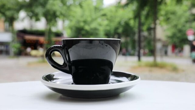 Cup of fresh hot coffee on the table of an outdoor cafe in Paris, France.