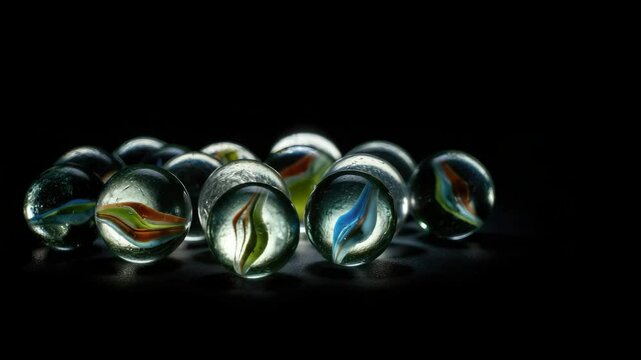 Assorted colorful marbles on black background illuminated dramatically