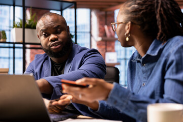 Obraz premium African american girl confronting her boyfriend about spending too much money, checking the balance on their joint savings account. Couple having some financial problems, banking debt.