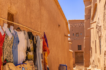 Colorful traditional dresses selling on the market streets of ancient Ait Benhaddou ksar village, Ouarzazate province, Morocco