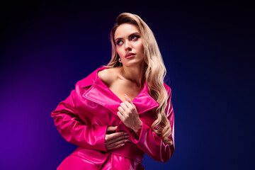 Stylish young woman in pink trench coat posing confidently against vibrant violet background