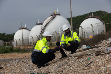 Two Environment staff with green safety jacket check Garbage polluting environment around factory