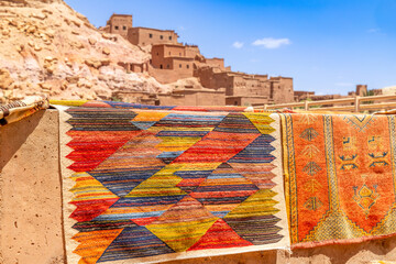 Colorful traditional carpets gifts selling on the market streets of ancient Ait Benhaddou ksar village, Ouarzazate province, Morocco