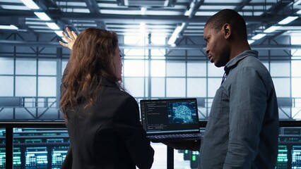 Software developers using AI tech on laptop in data center managing server virtualization. IT...