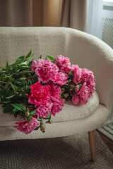 Bouquet of beautiful peonies on a pouf indoors