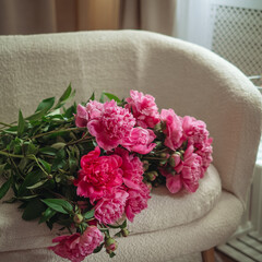 Bouquet of beautiful peonies on a pouf indoors