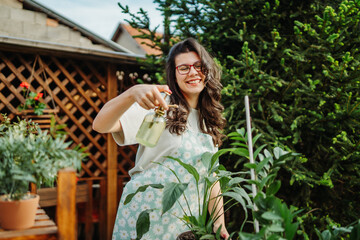 Young woman taking care of plants with water can and mister	
