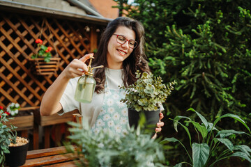 Young woman taking care of plants with water can and mister	