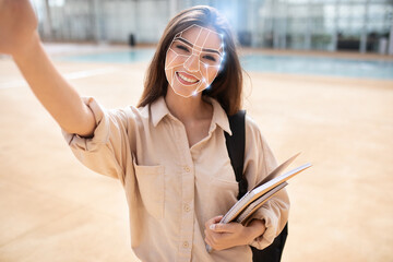 A person smiles while holding a notebook, engaged in a facial recognition check during a technology...