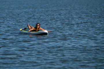 Caucasian woman posing on a SUP board. Summer sport.