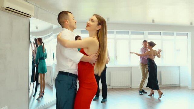 Couple of young guy and young woman dancing waltz in studio 