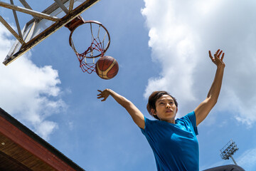 Denpasar, 13 Feb 23: A young athlete performs a slam dunk at a street basketball court under the midday sun in Bali, Indonesia.