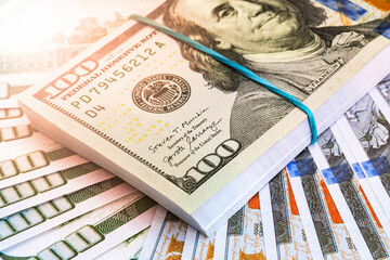 close-up of stacked US hundred dollar bills against a background of mixed currency.