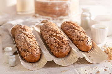 Crispy and hot wholegrain baguettes baked on baking tray.