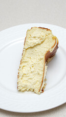 Close-up of a slice of New York-style cheesecake on a white plate.