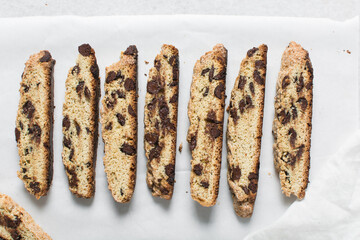 Overhead view of chocolate chip biscotti on white parchment lined tray, flatlay of slices of biscotti cookies or twice baked cookies