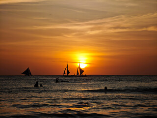 Boracay island sunset view with sailboat in horizon. Amazing topical sunset during a golden hour in Philippines sea waters