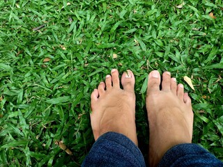 Feet stepping on green grass, walking barefoot on the grass gives a unique sensation