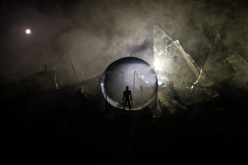 A silhouette of a person against the background of shattered glass. An abstract world made of glass shards. Surreal concept. Table top decoration.