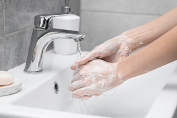 Woman washing hands at sink in bathroom, closeup