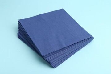 Stack of disposable paper handkerchiefs on light blue background, closeup