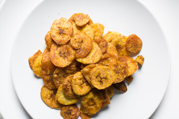 Overhead view of plantain chips on a white countertop, top view of fried ripe plantains on a white background