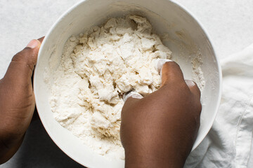 Overhead view of steamed bun dough being kneaded on a white background, top view of mantou dough being mixed, process of making steamed buns