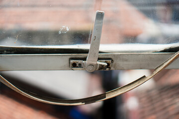 Obraz premium An abstract close-up image highlights an aged window mechanism with a metallic handle, showcasing textures and muted tones for backgrounds, architectural details, and industrial themes.