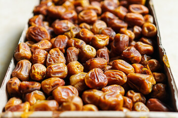 A captivating close-up reveals a box overflowing with luscious dates, their deep amber hues promising a taste of natural sweetness. A tempting display of nutritious snacks, perfect for healthy eating.