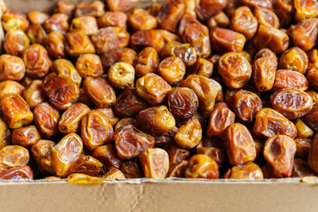 A close-up shows a box filled to the brim with delectable, glistening dates, their rich amber hues suggesting a natural sweetness and a satisfyingly chewy texture, perfect for snacking and baking.