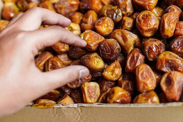 A close-up captures the texture and richness of dates being selected. The image emphasizes the healthy snack's natural sweetness, freshness, and inviting appeal for various uses.